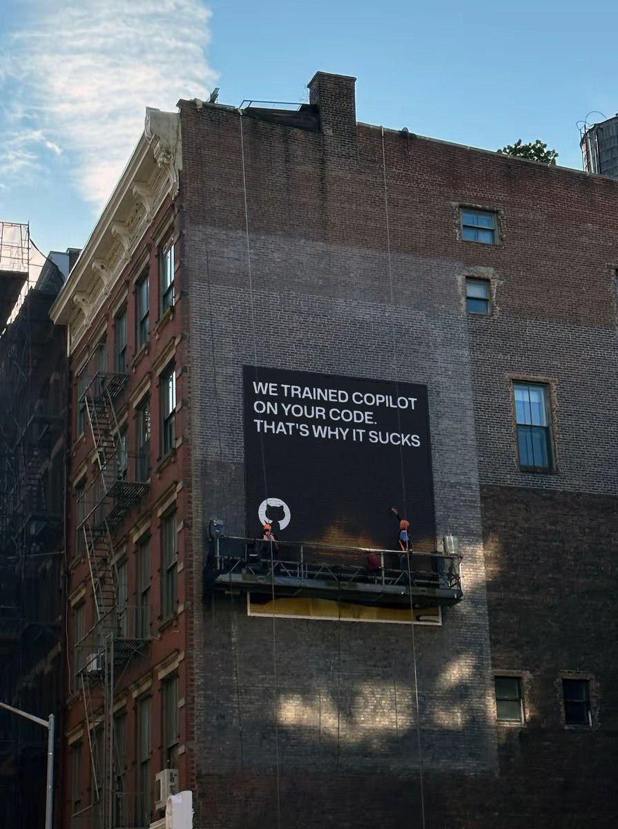 Billboard with text: 'We trained Copilot on your code. That's why it sucks' with workers on a scaffold in front of a brick wall.